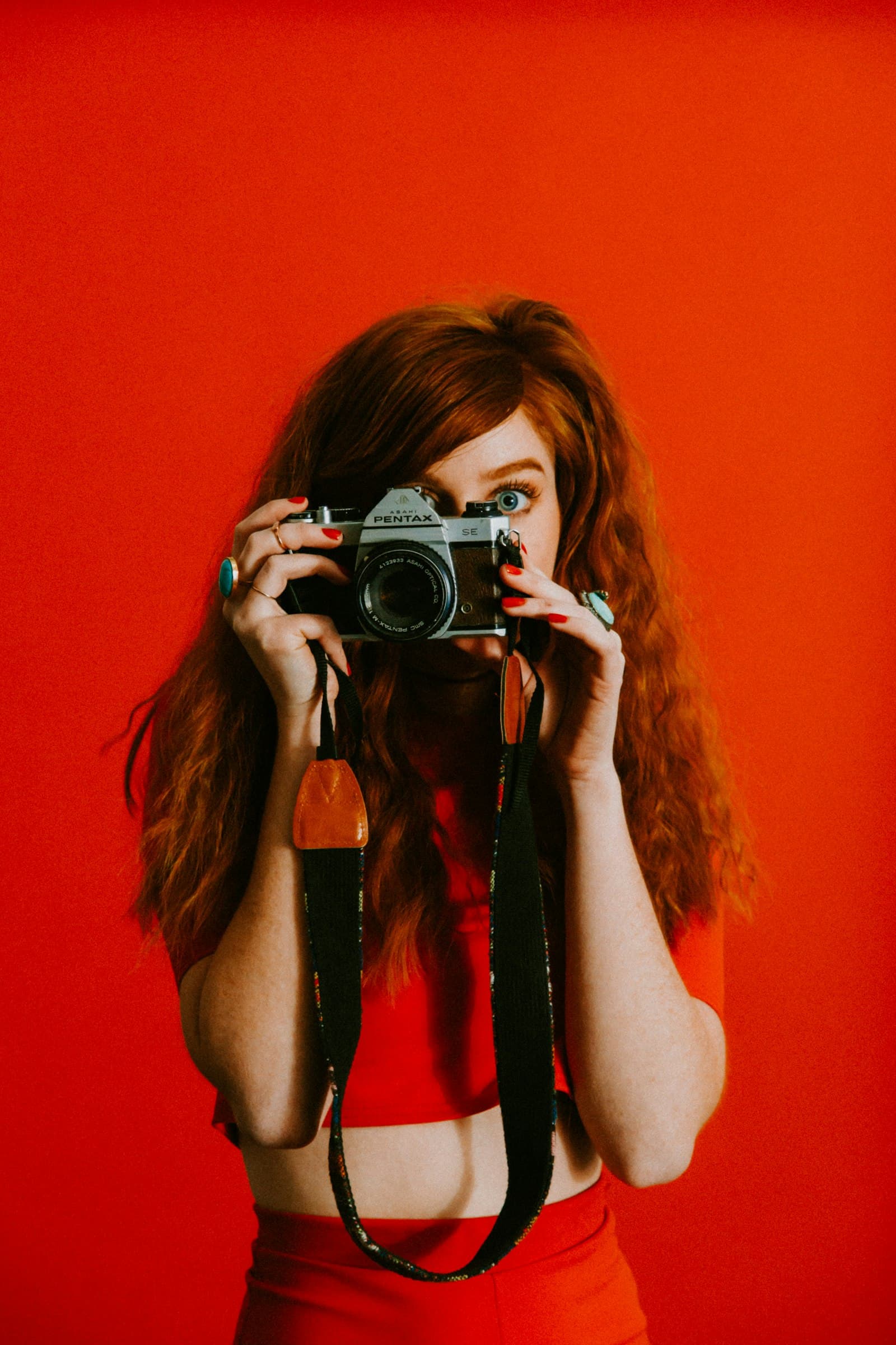 A creator holding a film camera against a red backdrop